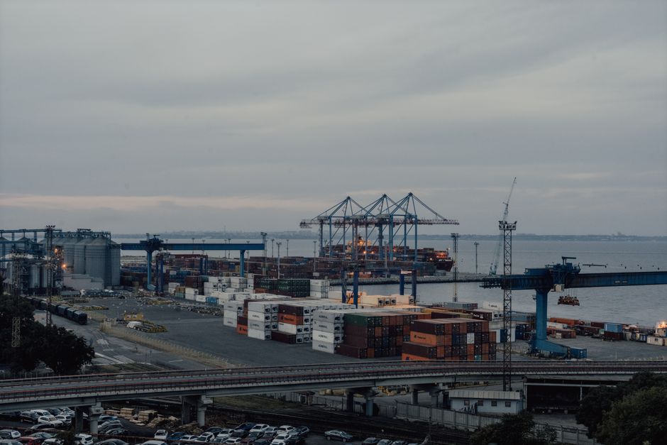 Aerial view of Odesa port, showcasing cranes, containers, and industrial activity at sunset.